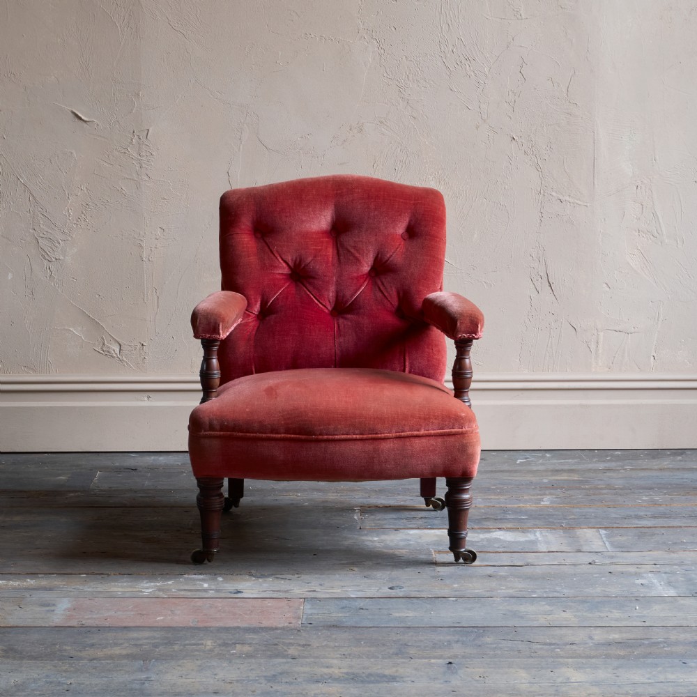 Victorian open armchair featuring deep buttoned rose pink velvet upholstery, turned wooden front legs, and brass castors. View III