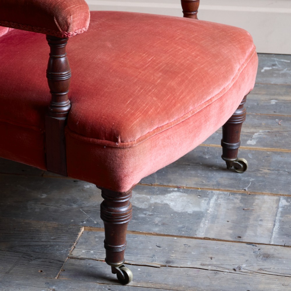 Victorian open armchair featuring deep buttoned rose pink velvet upholstery, turned wooden front legs, and brass castors. View VII