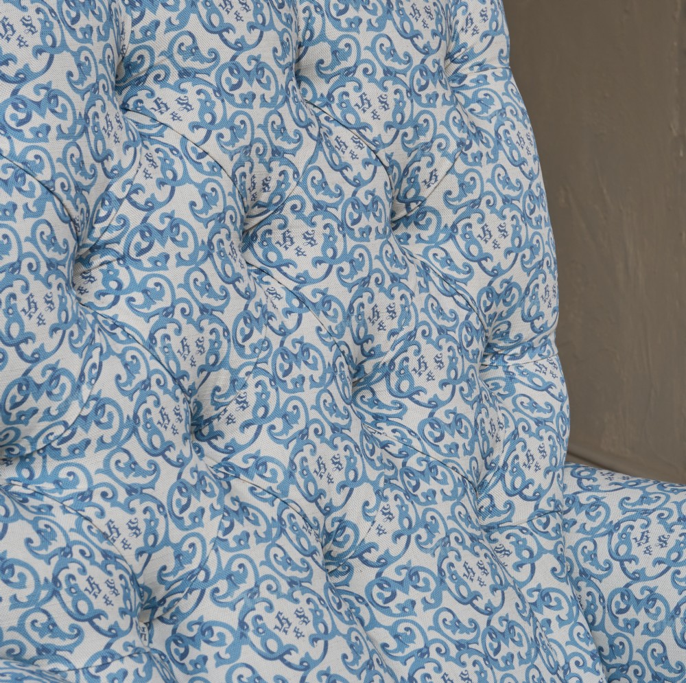 A Victorian button-back armchair upholstered in blue and white pattern printed ticking fabric with turned timber front legs on brass castors. View VII