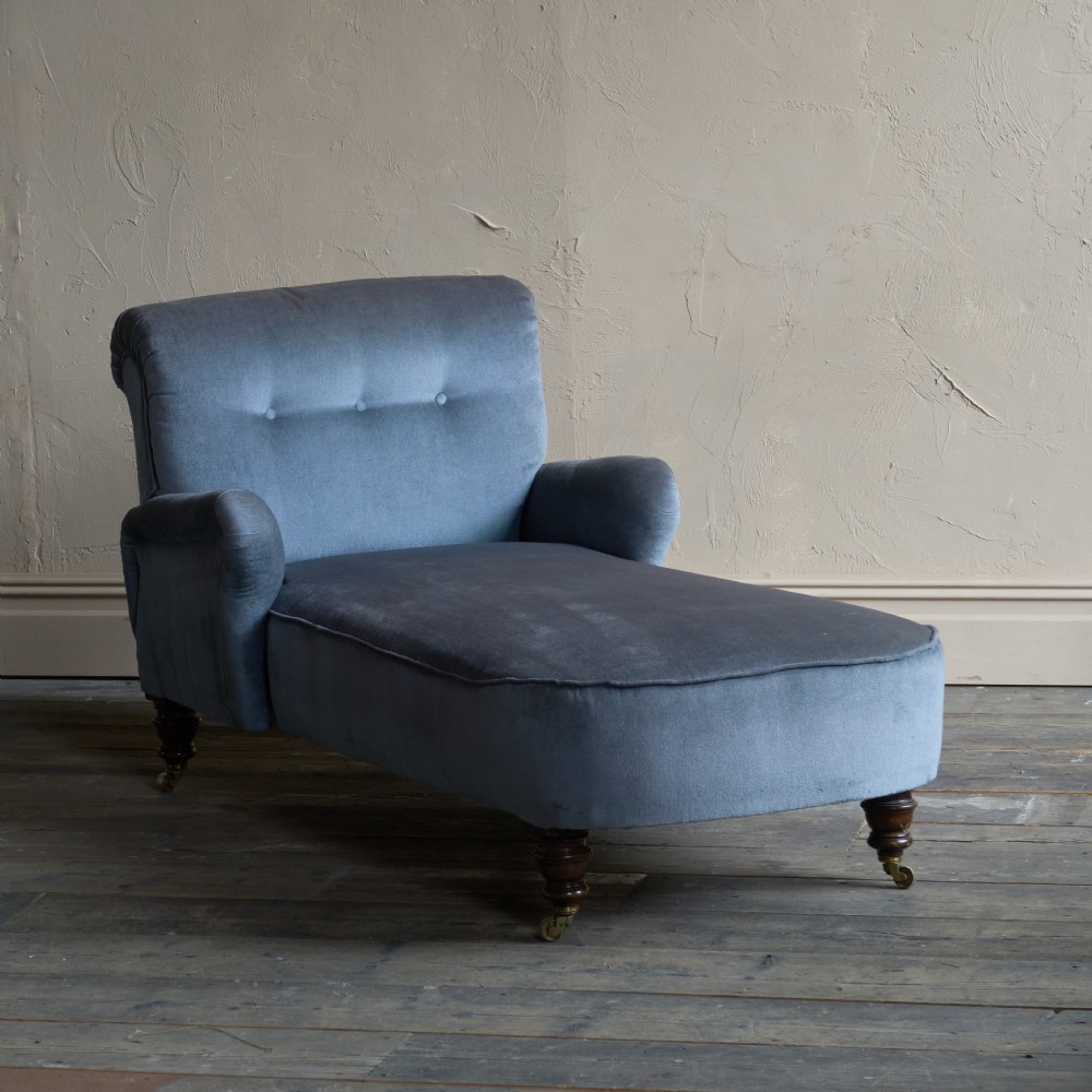 A Victorian slate blue velvet upholstered reclining day bed with a tufted backrest, turned wood legs, and brass castors.