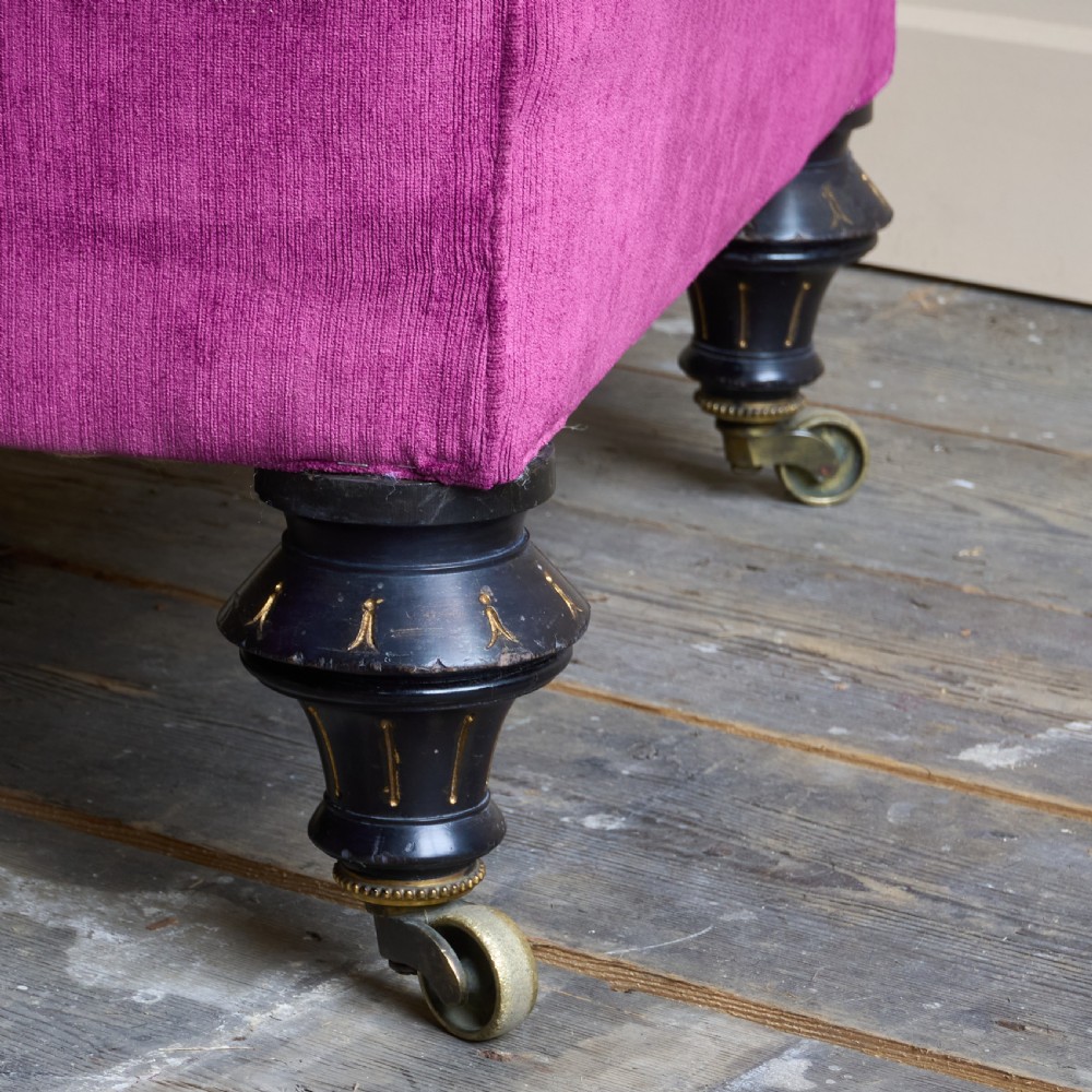 An antique velvet Chesterfield sofa featuring deep button tufting, rolled arms, and dark turned wooden legs with brass castors. View VII