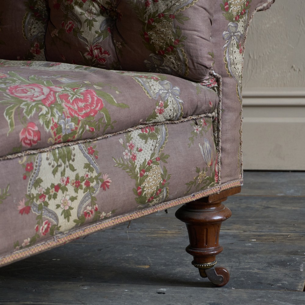 A Victorian deep-buttoned Chesterfield sofa upholstered in a floral fabric with rolled arms and turned mahogany legs on brass castors. View IX