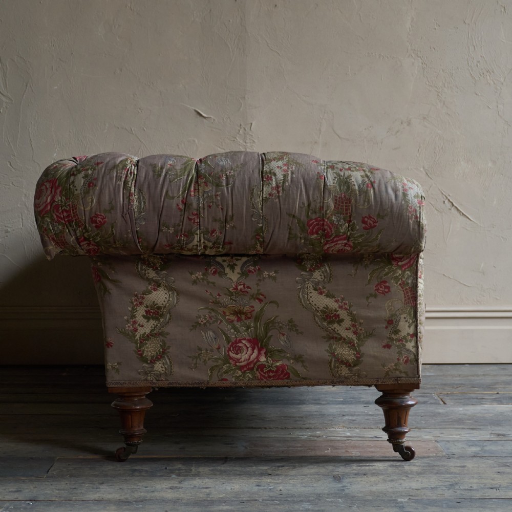 A Victorian deep-buttoned Chesterfield sofa upholstered in a floral fabric with rolled arms and turned mahogany legs on brass castors. View X