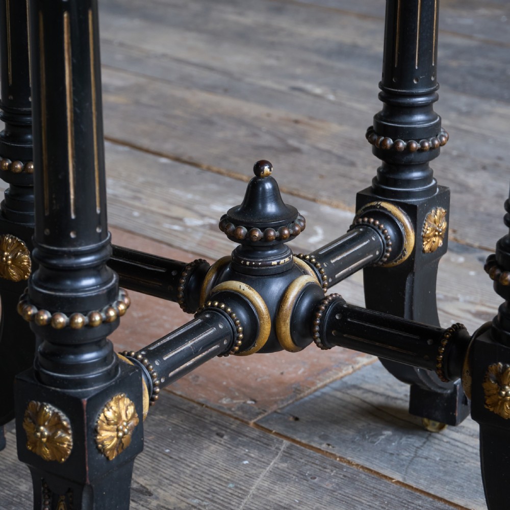 An octagonal ebonised side table featuring turned legs with gilt accents, central stretchers with carved rosettes, and brass castors. View III