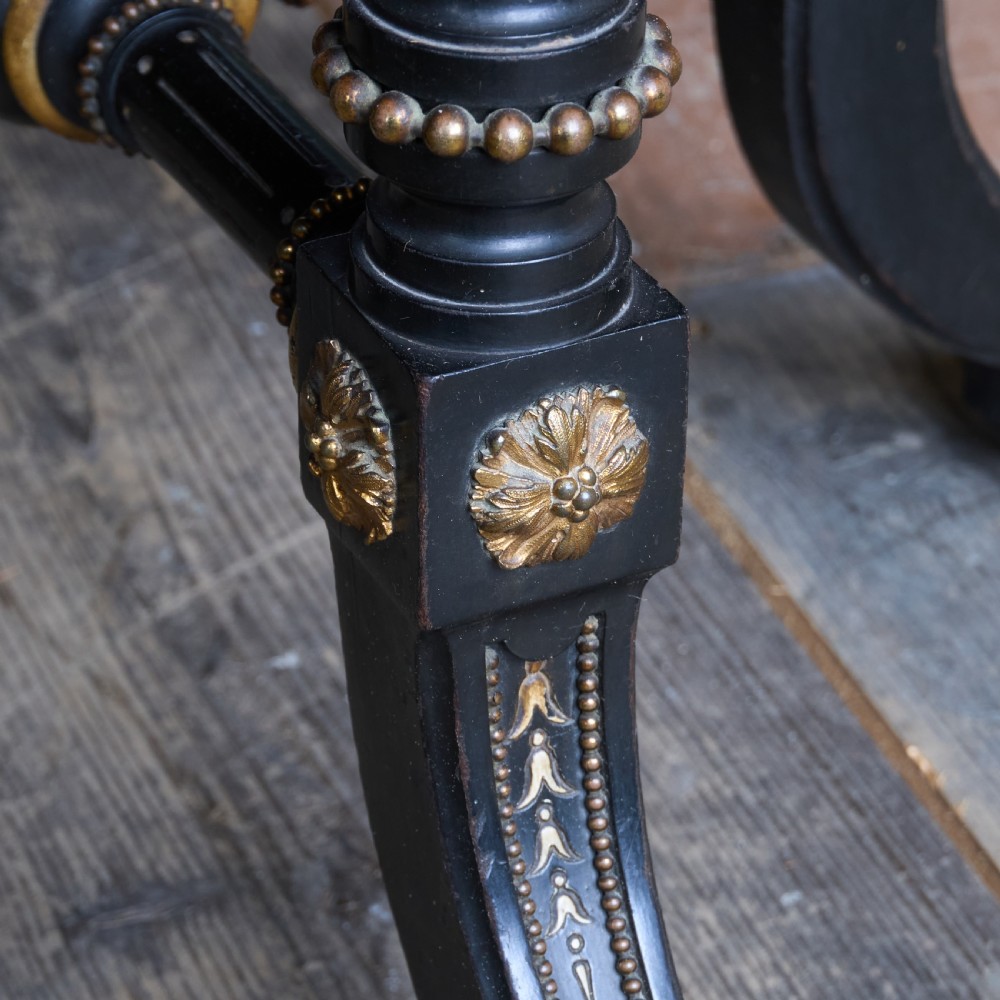 An octagonal ebonised side table featuring turned legs with gilt accents, central stretchers with carved rosettes, and brass castors. View VII