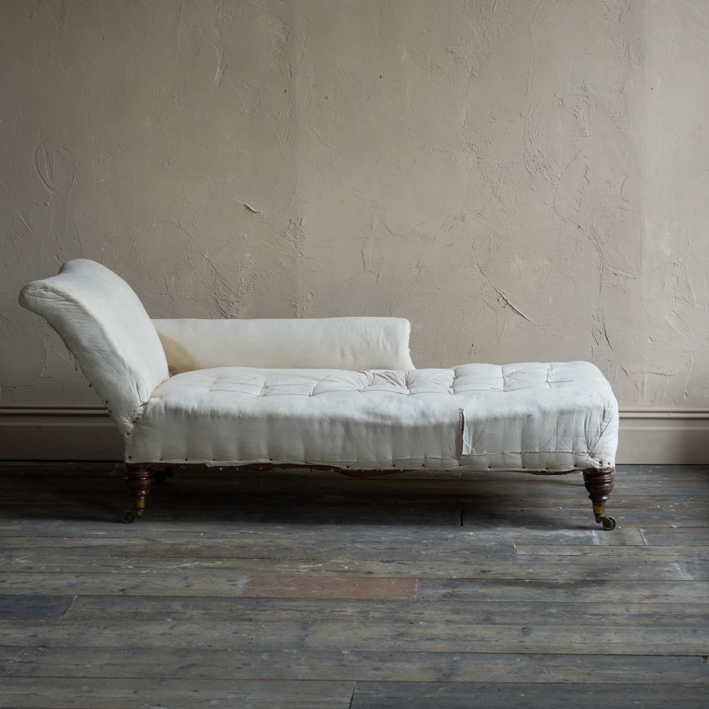 An antique calico-covered chaise longue features turned wooden legs with brass castors and a button-tufted seat. View III