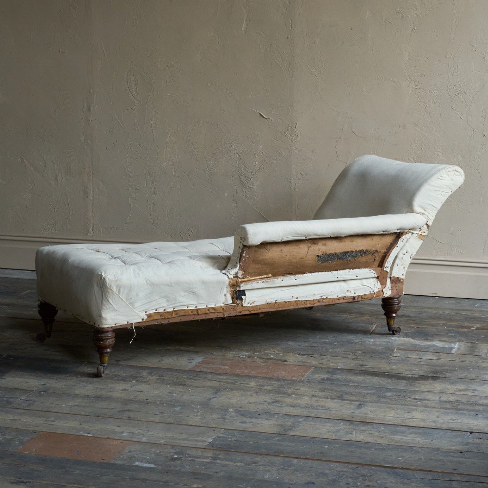 An antique calico-covered chaise longue features turned wooden legs with brass castors and a button-tufted seat. View IV