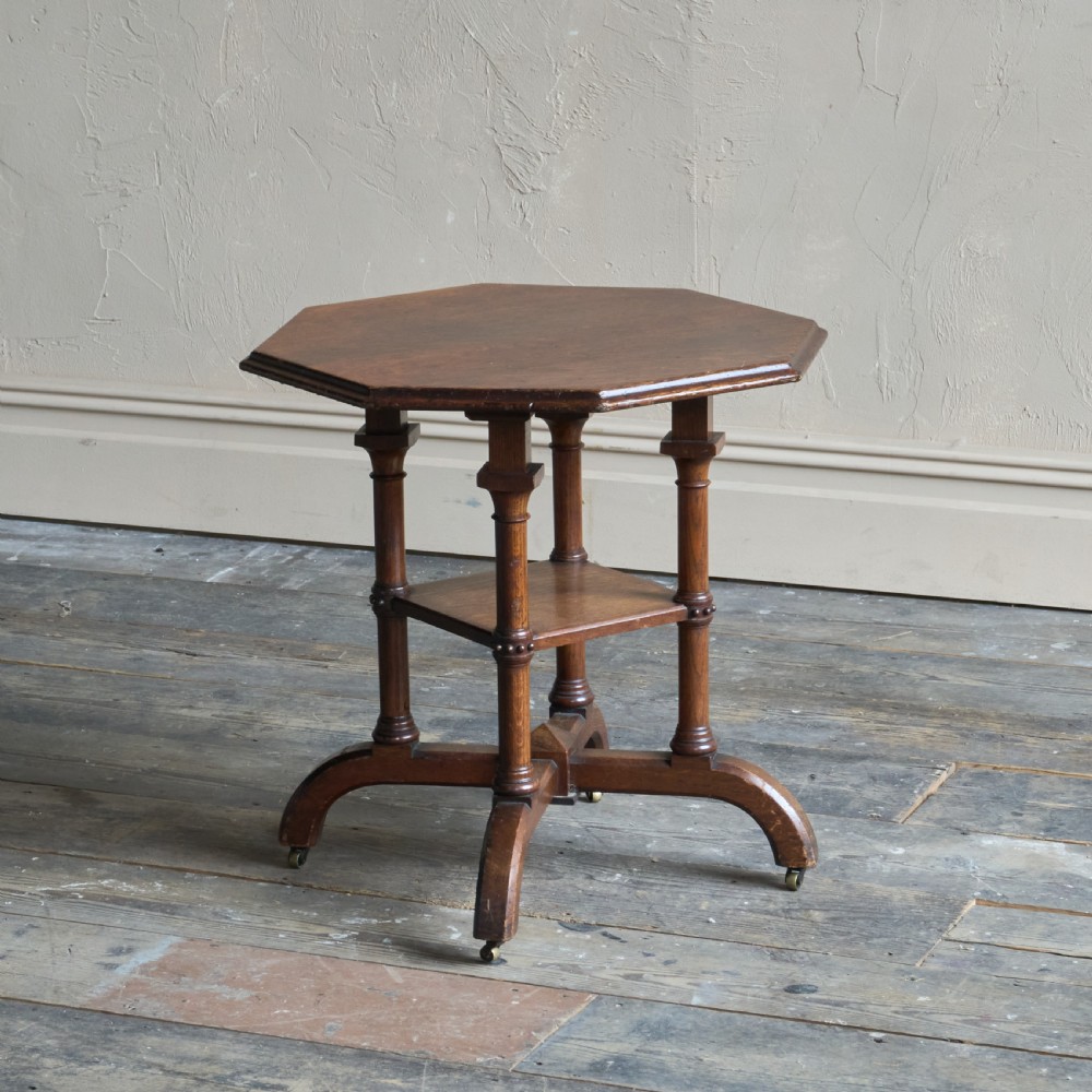 An octagonal Victorian walnut side table featuring turned legs, a lower tier shelf, and brass castors on curved feet. View II