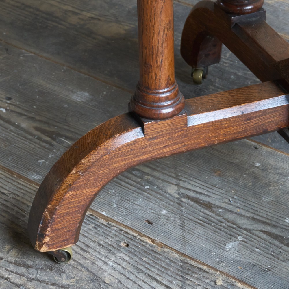 An octagonal Victorian walnut side table featuring turned legs, a lower tier shelf, and brass castors on curved feet. View V