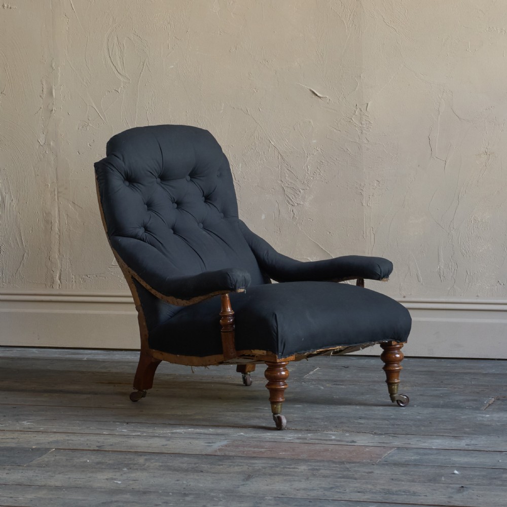 A Victorian open armchair upholstered in black calico, featuring a button-tufted inclined backrest, turned wooden arm uprights, and turned front legs fitted with brass castors. View III
