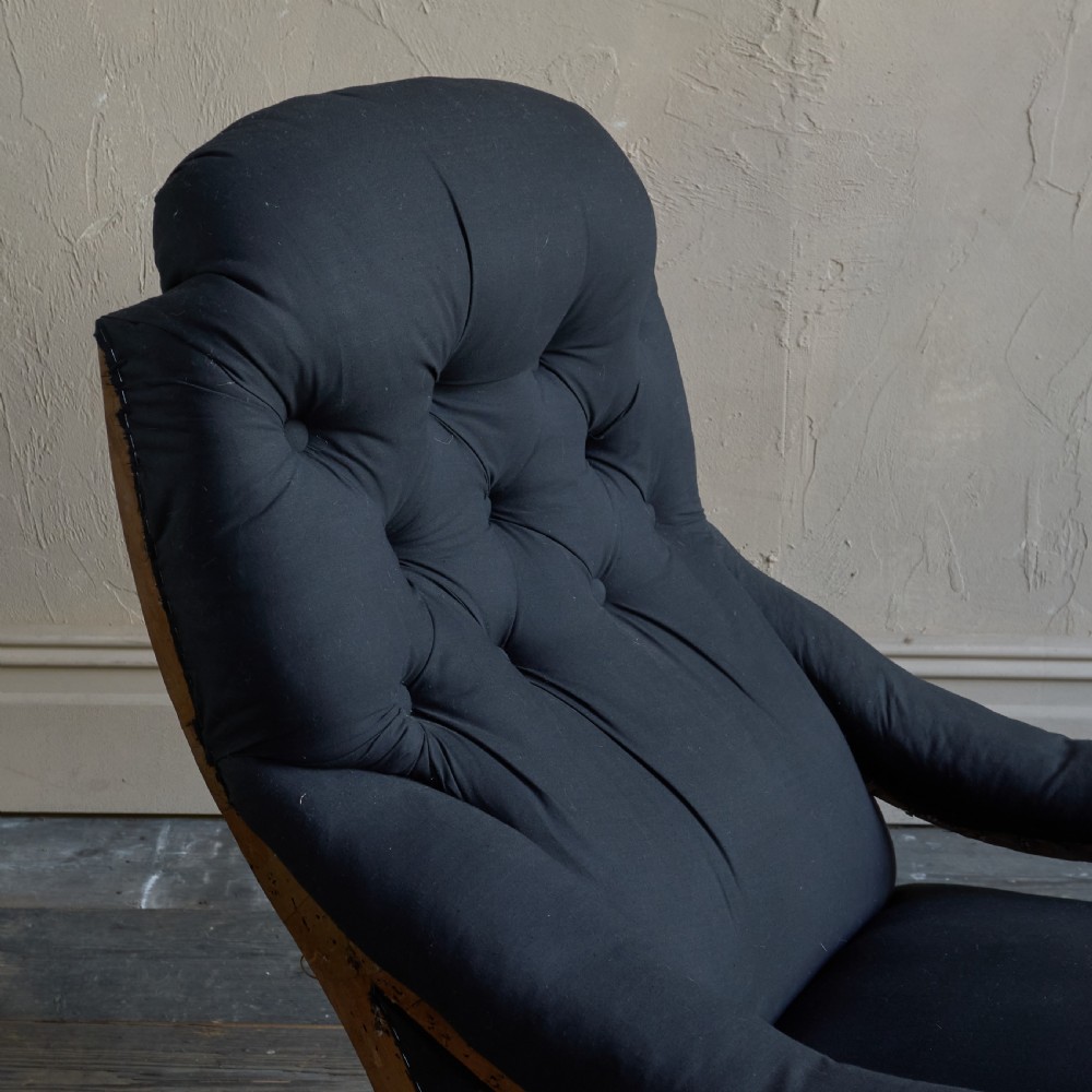 A Victorian open armchair upholstered in black calico, featuring a button-tufted inclined backrest, turned wooden arm uprights, and turned front legs fitted with brass castors. View VIII