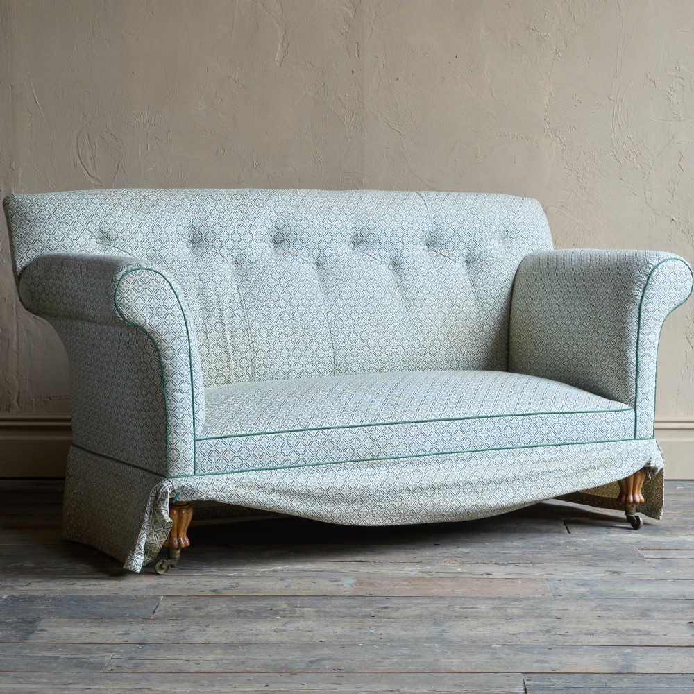 A Regency style upholstered library sofa with button-backed backrest, scrolled arms, pale green patterned fabric with dark piping, and turned legs on brass castors. View II