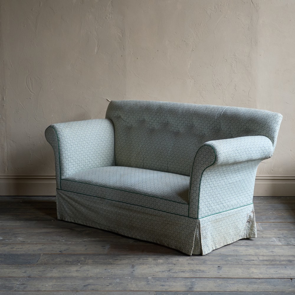 A Regency style upholstered library sofa with button-backed backrest, scrolled arms, pale green patterned fabric with dark piping, and turned legs on brass castors. View III
