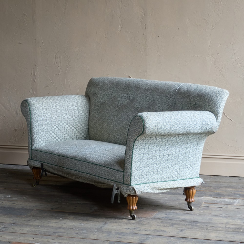 A Regency style upholstered library sofa with button-backed backrest, scrolled arms, pale green patterned fabric with dark piping, and turned legs on brass castors. View V