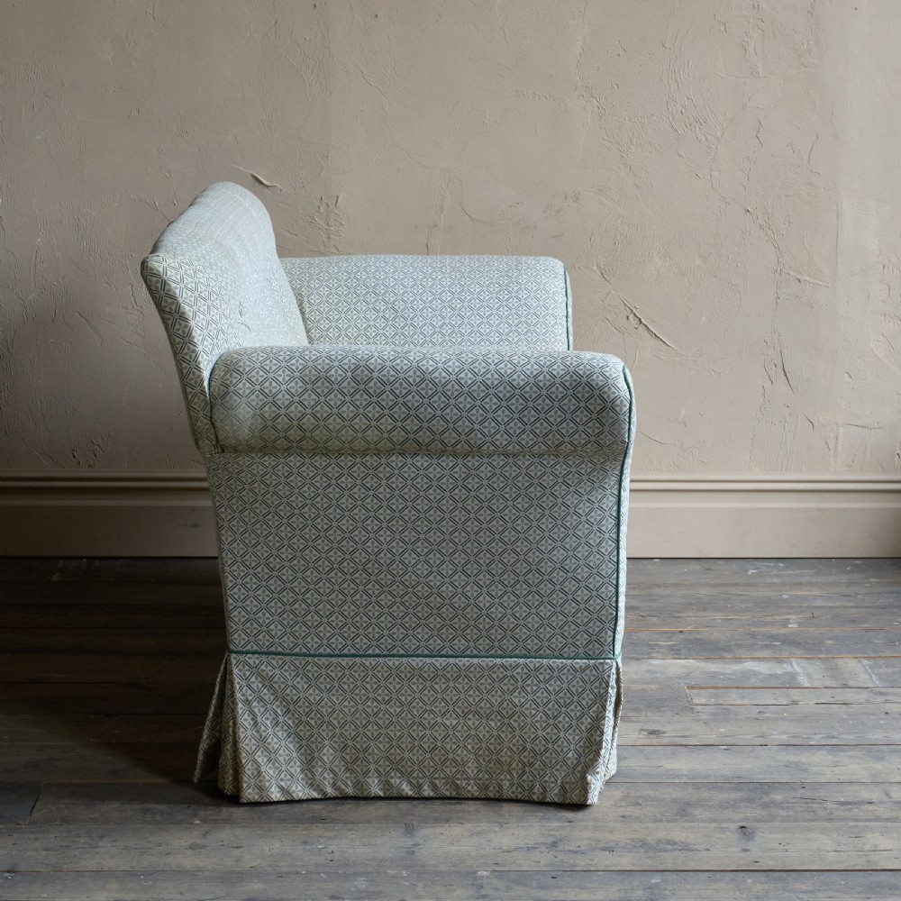A Regency style upholstered library sofa with button-backed backrest, scrolled arms, pale green patterned fabric with dark piping, and turned legs on brass castors. View VI