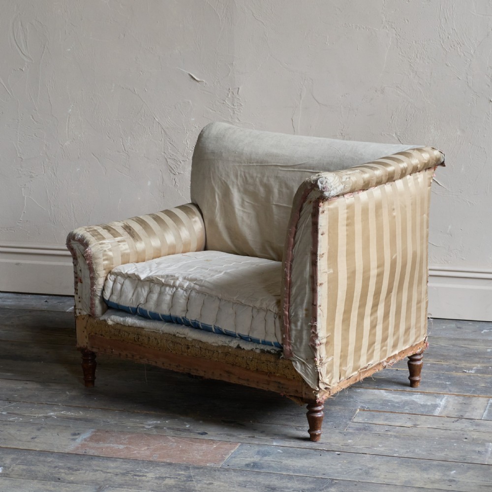 An antique upholstered corner armchair featuring turned wooden legs, striped satin fabric, and a thick tufted squab cushion. View VI