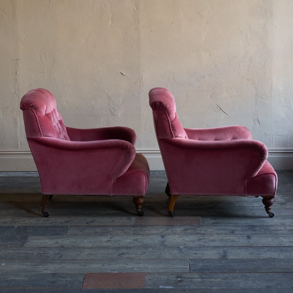 A pair of deep-seated Howard style armchairs upholstered in rose pink velvet featuring button-tufted backrests and turned wooden legs on castors. View VI