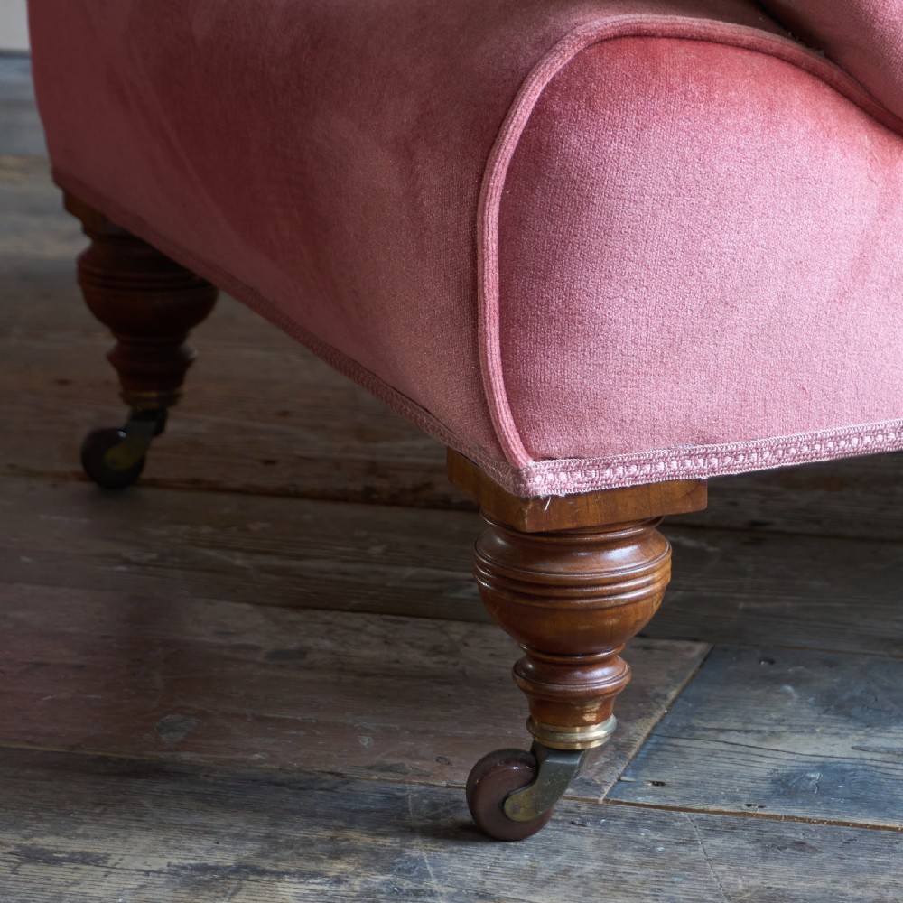 A pair of deep-seated Howard style armchairs upholstered in rose pink velvet featuring button-tufted backrests and turned wooden legs on castors. View VIII
