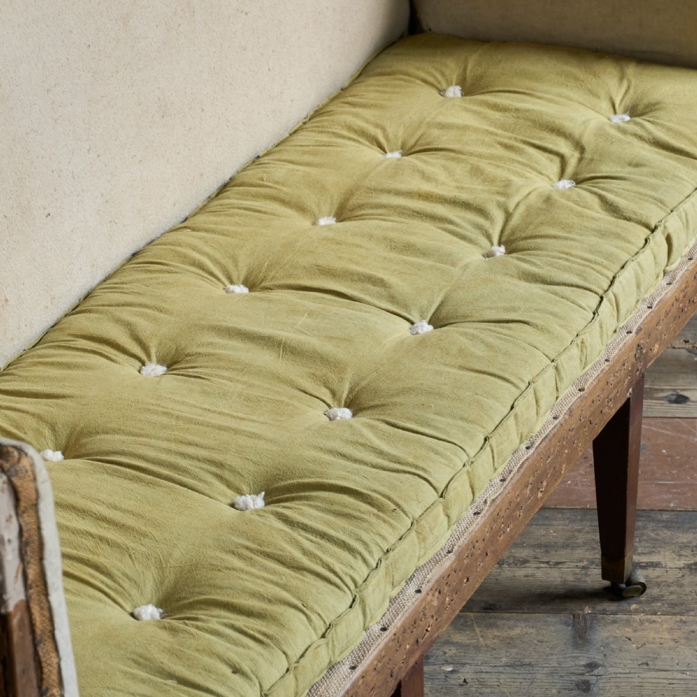An antique Georgian square-back sofa featuring exposed wooden framing, eight legs with castors, and a yellow tufted seat cushion. View VI