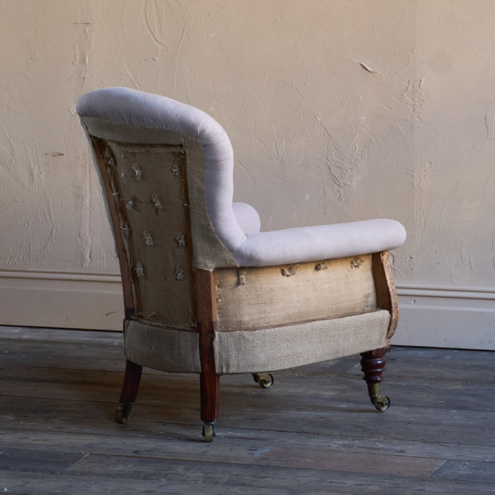A Regency period button-backed armchair upholstered in pale grey fabric with lyre-shaped front arm supports and turned mahogany legs on brass castors. View V