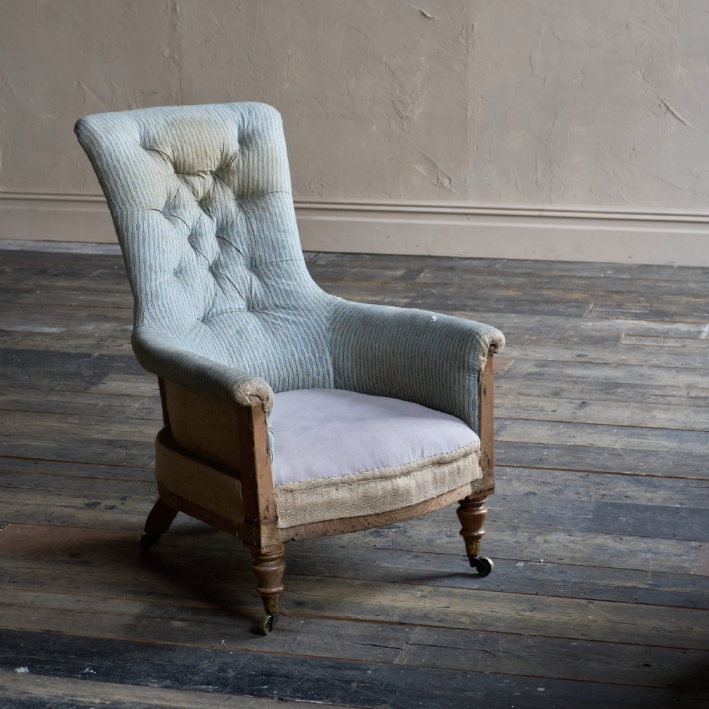 A Regency high-back library armchair featuring button-backed blue striped fabric, exposed hessian base, turned front wooden legs, and brass castors. View II