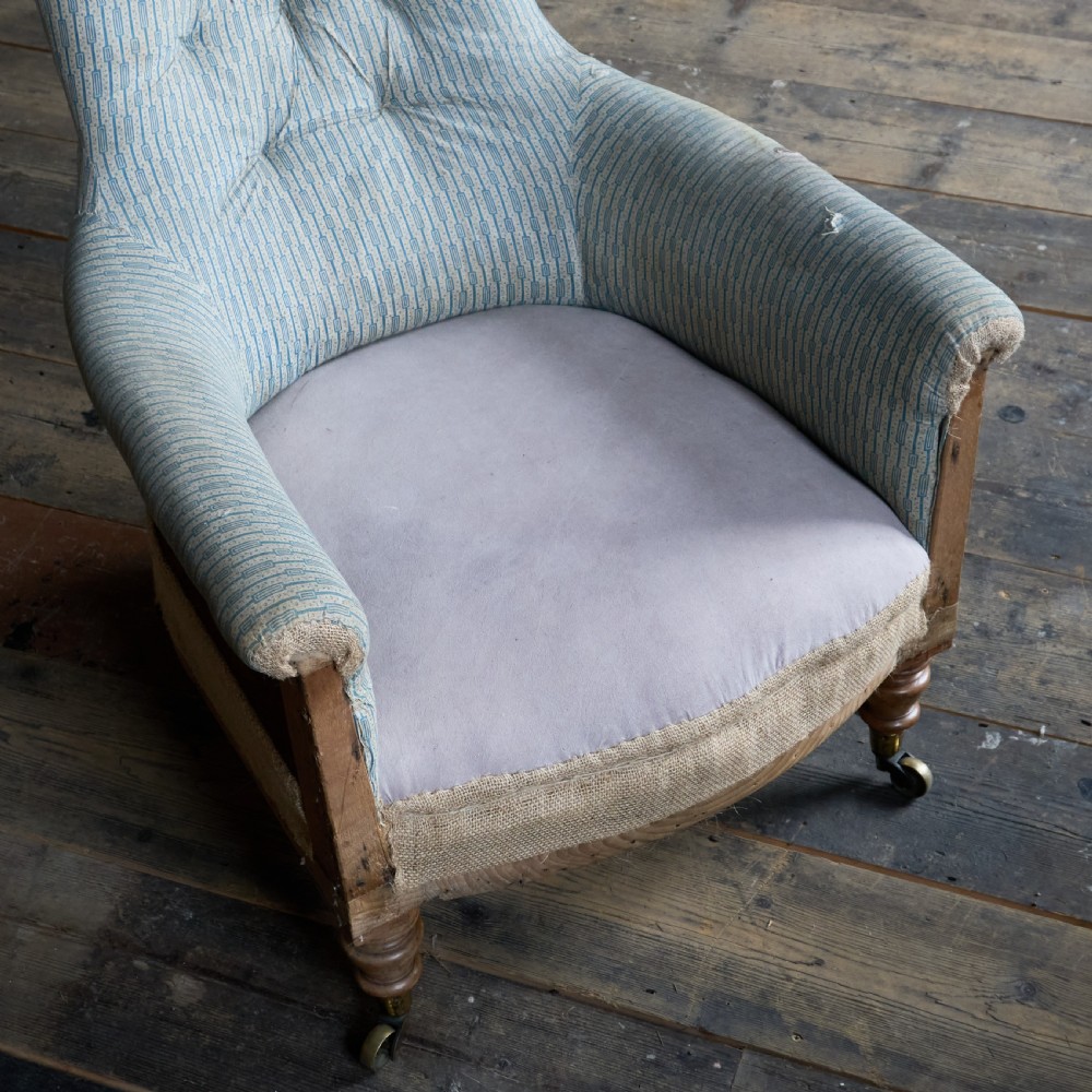 A Regency high-back library armchair featuring button-backed blue striped fabric, exposed hessian base, turned front wooden legs, and brass castors. View VI