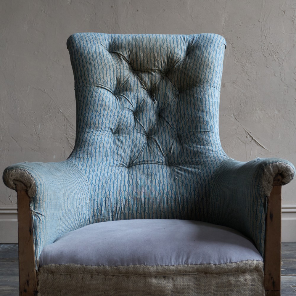 A Regency high-back library armchair featuring button-backed blue striped fabric, exposed hessian base, turned front wooden legs, and brass castors. View VII
