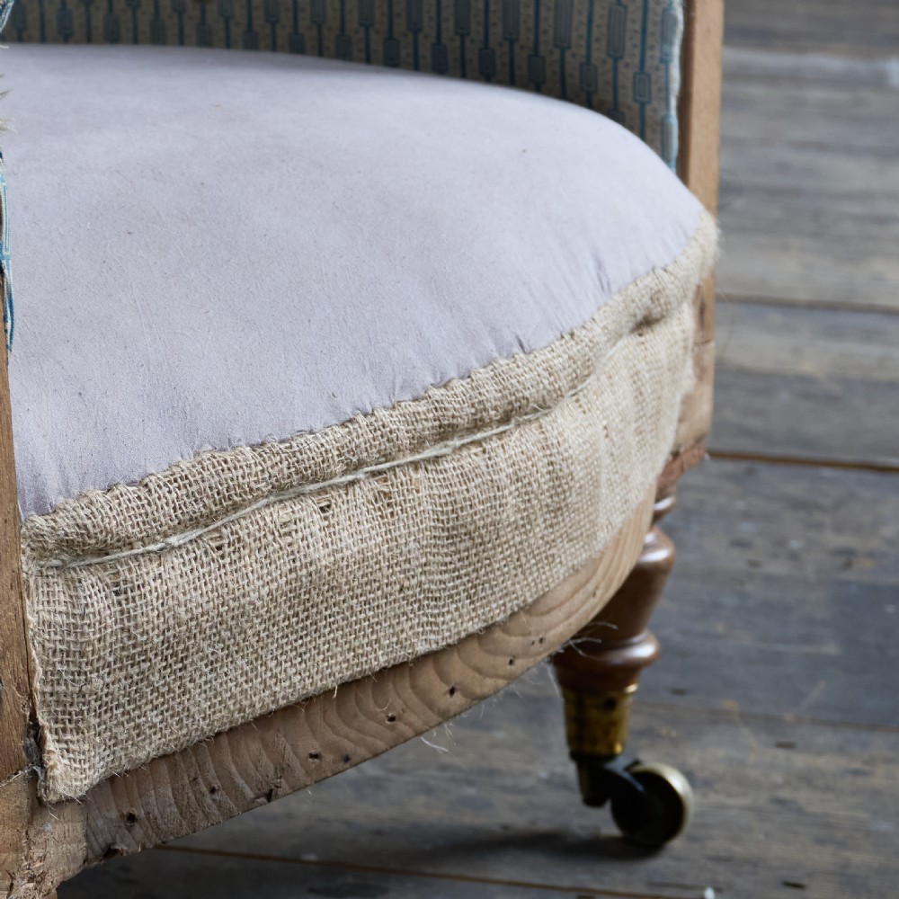 A Regency high-back library armchair featuring button-backed blue striped fabric, exposed hessian base, turned front wooden legs, and brass castors. View VIII