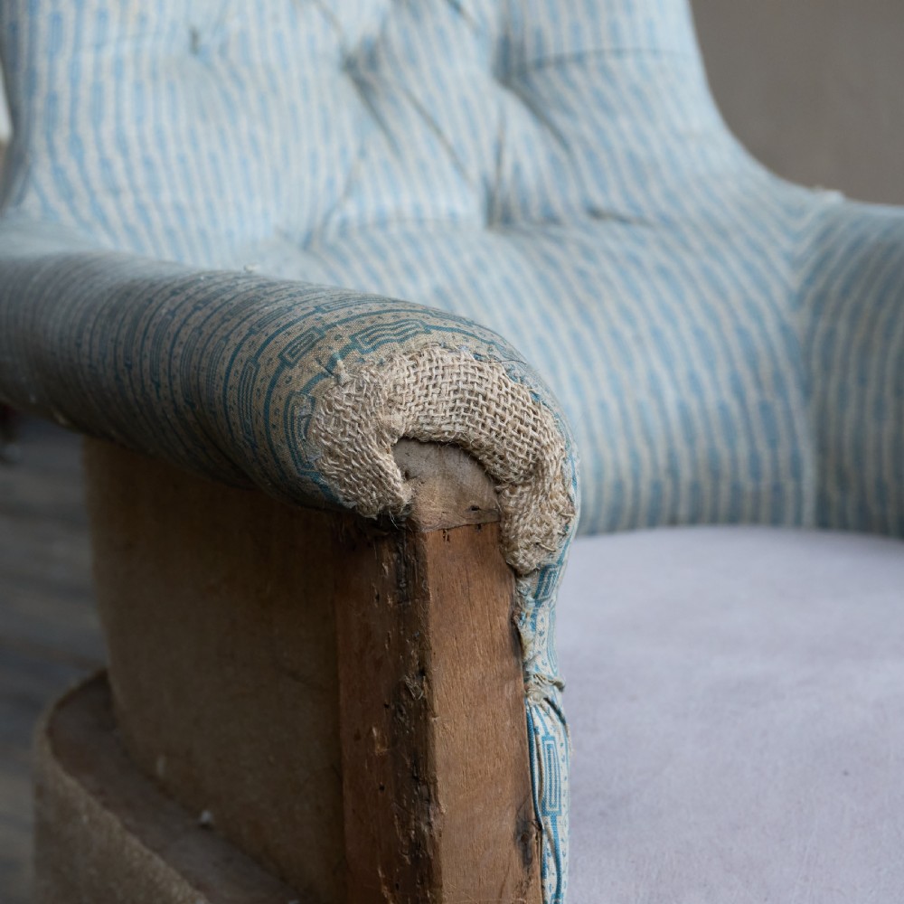 A Regency high-back library armchair featuring button-backed blue striped fabric, exposed hessian base, turned front wooden legs, and brass castors. View IX