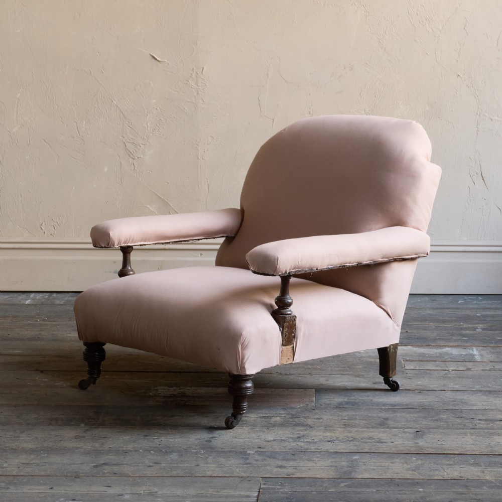 An antique upholstered armchair covered in plain beige calico fabric, featuring turned wooden legs with castors and padded armrests. View II