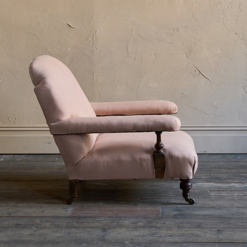 An antique upholstered armchair covered in plain beige calico fabric, featuring turned wooden legs with castors and padded armrests. View IV