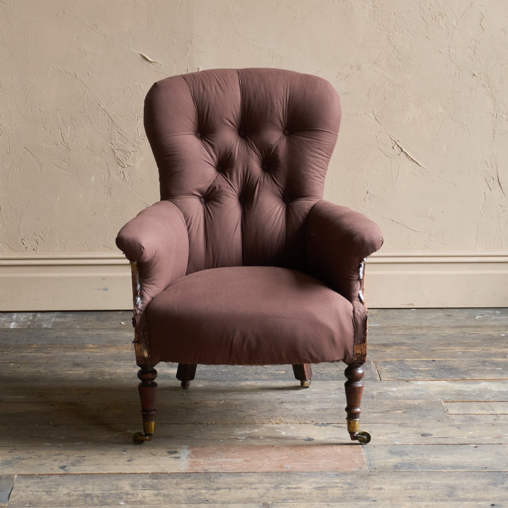An antique Regency spoon-back armchair upholstered in dark brown fabric with button tufting and wooden castors. View II