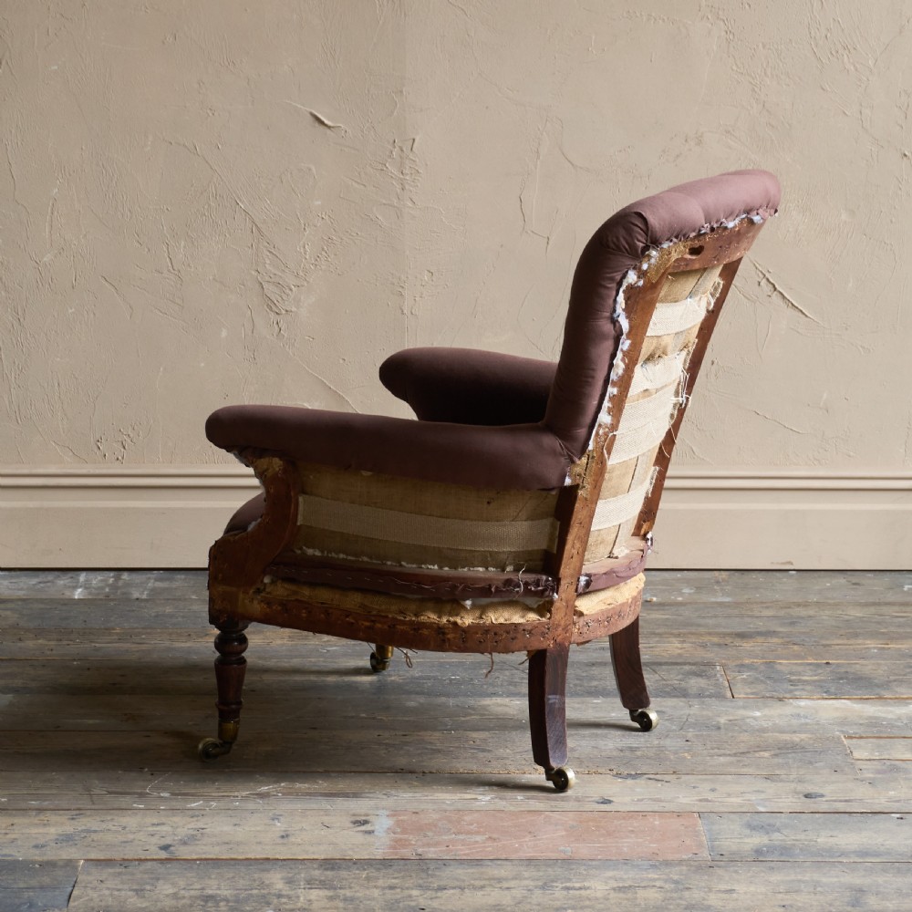 An antique Regency spoon-back armchair upholstered in dark brown fabric with button tufting and wooden castors. View IV