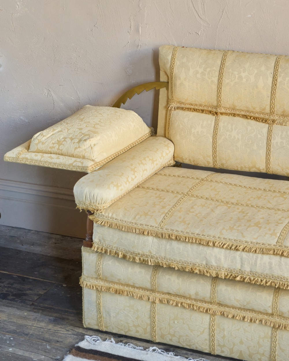 An antique gold damask Knole sofa with high drop-down side arms, fringed trim, and vertical panel upholstery. View V
