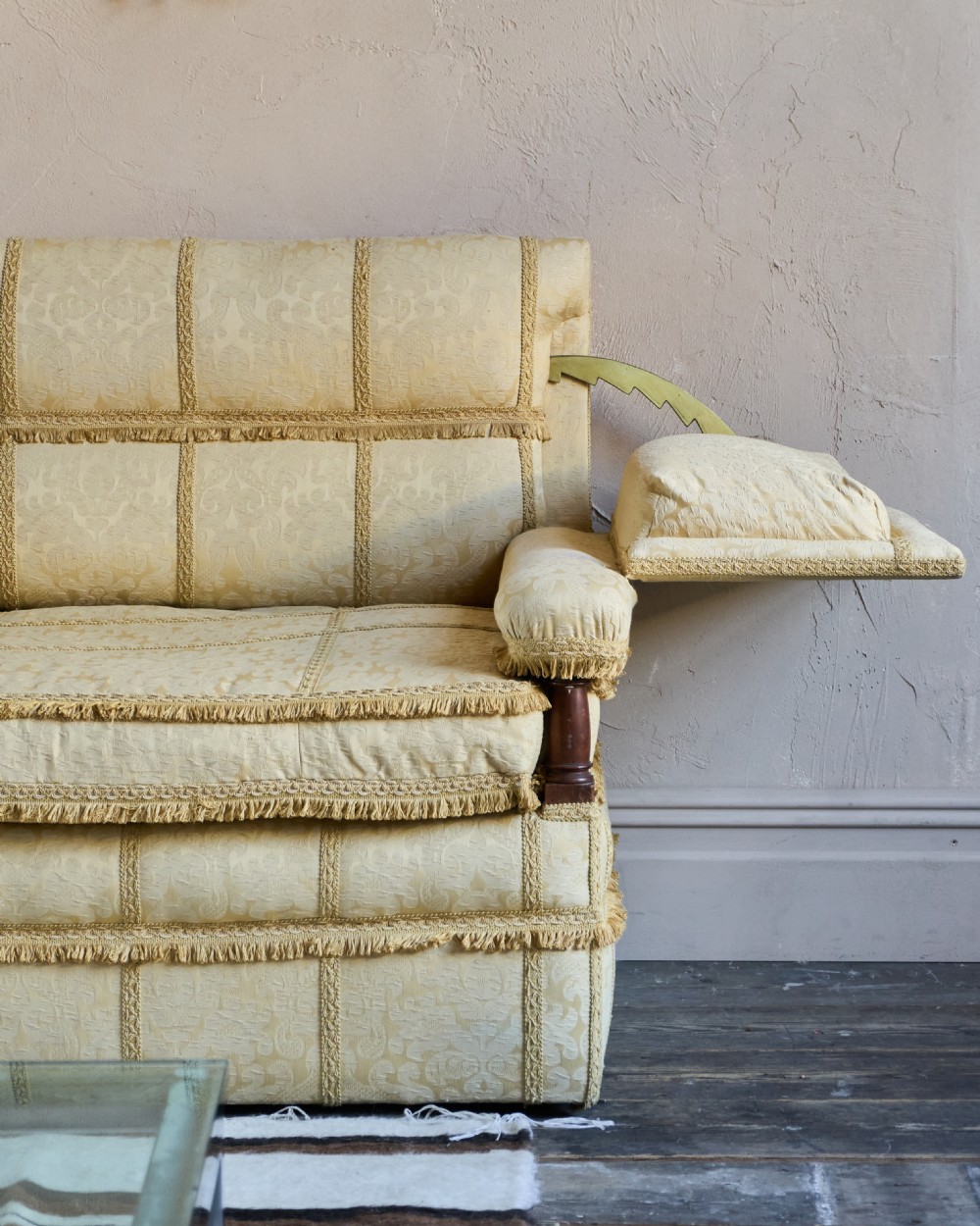 An antique gold damask Knole sofa with high drop-down side arms, fringed trim, and vertical panel upholstery. View VI