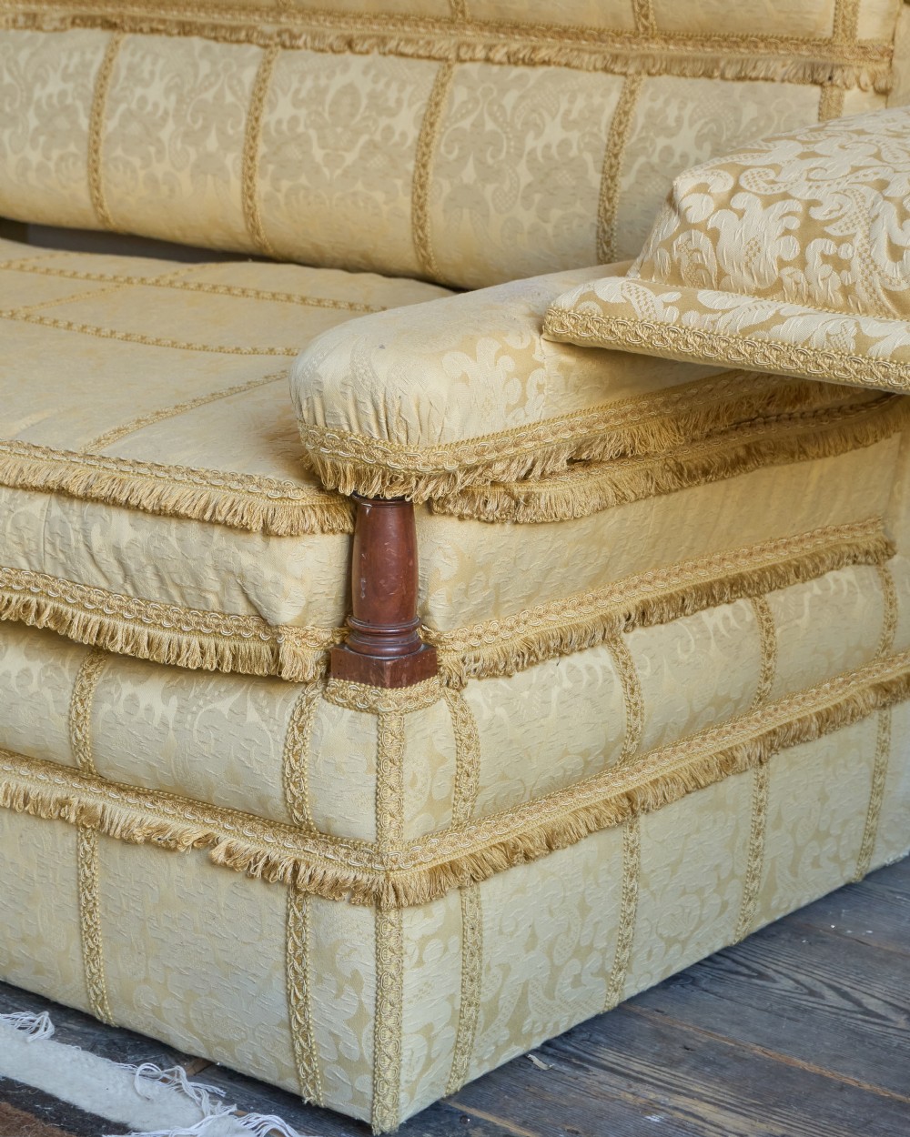 An antique gold damask Knole sofa with high drop-down side arms, fringed trim, and vertical panel upholstery. View VII
