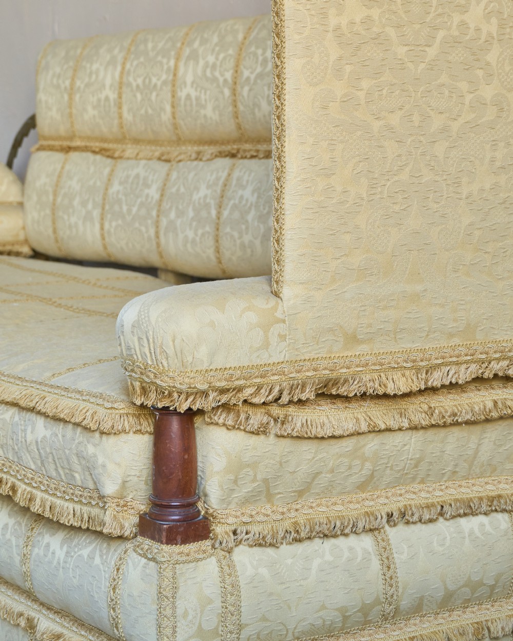 An antique gold damask Knole sofa with high drop-down side arms, fringed trim, and vertical panel upholstery. View IX