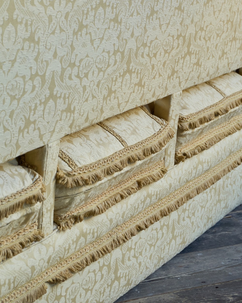 An antique gold damask Knole sofa with high drop-down side arms, fringed trim, and vertical panel upholstery. View XI