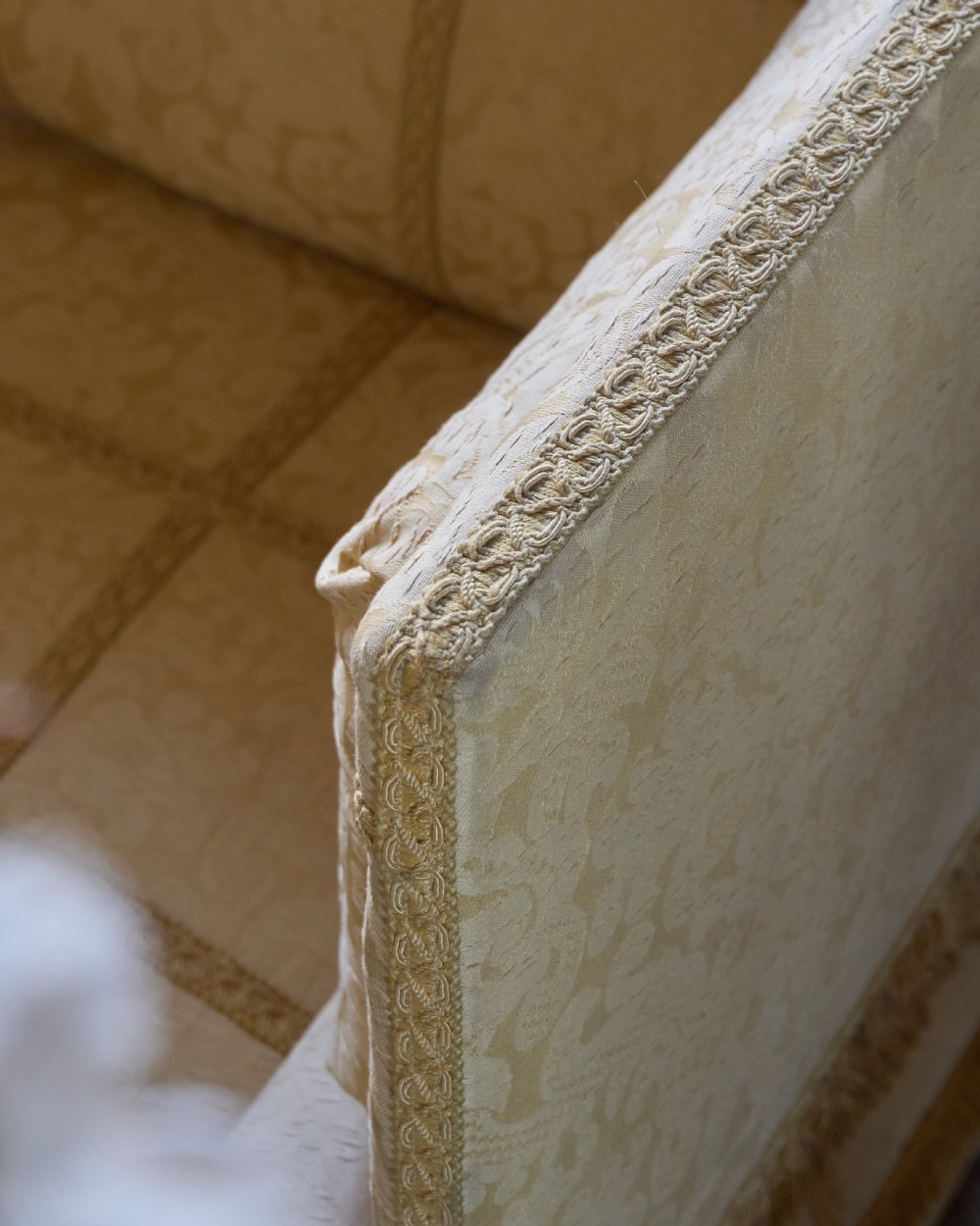 An antique gold damask Knole sofa with high drop-down side arms, fringed trim, and vertical panel upholstery. View XIII