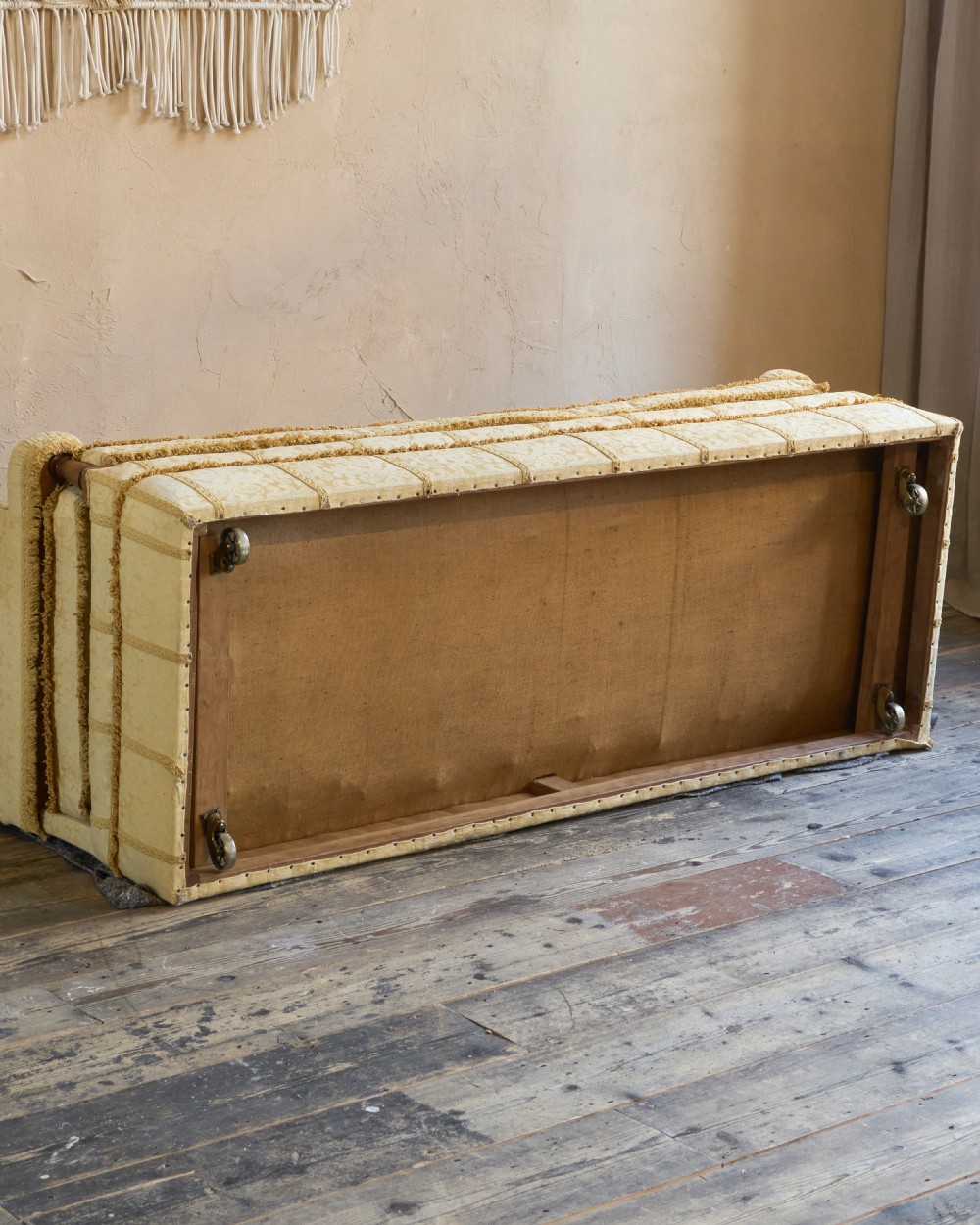 An antique gold damask Knole sofa with high drop-down side arms, fringed trim, and vertical panel upholstery. View XIV