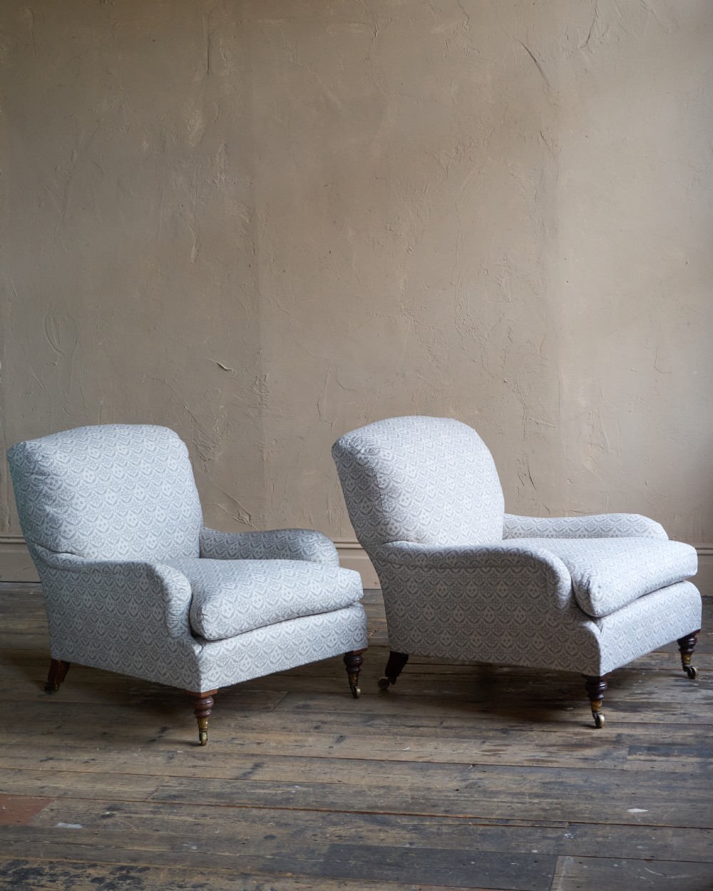 A pair of Victorian Howard and Sons Grafton style armchairs upholstered in patterned grey fabric with turned timber legs on brass castors. View III