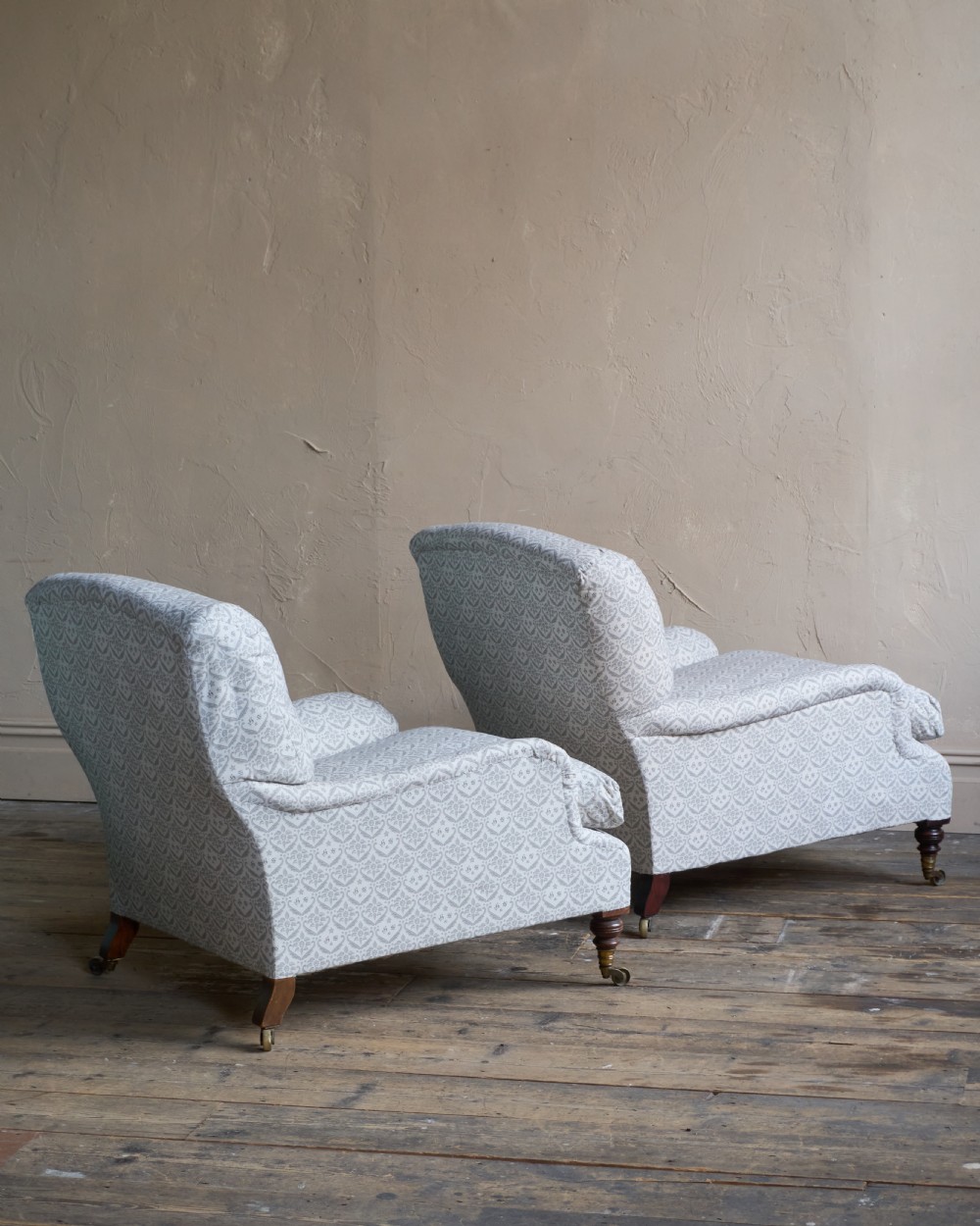 A pair of Victorian Howard and Sons Grafton style armchairs upholstered in patterned grey fabric with turned timber legs on brass castors. View V