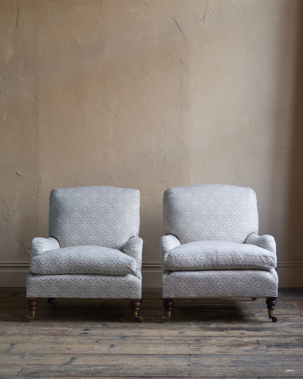 A pair of Victorian Howard and Sons Grafton style armchairs upholstered in patterned grey fabric with turned timber legs on brass castors. View VIII