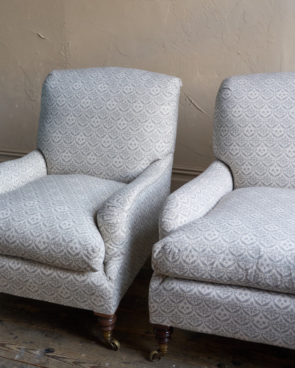 A pair of Victorian Howard and Sons Grafton style armchairs upholstered in patterned grey fabric with turned timber legs on brass castors. View IX