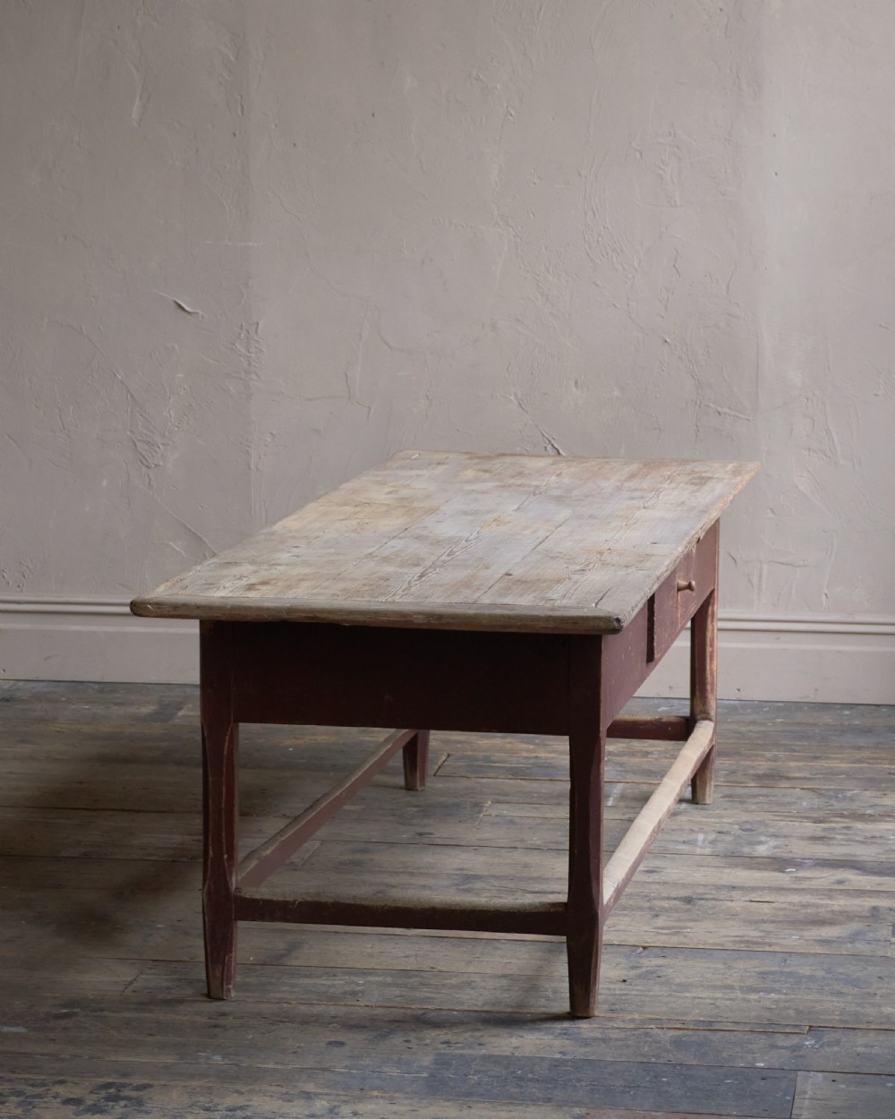 An antique Swedish kitchen table featuring an untreated scrubbed pine top, a single side drawer, and a Falu red painted apron and leg framework with stretchers. View II