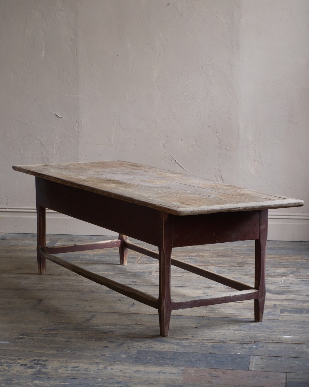 An antique Swedish kitchen table featuring an untreated scrubbed pine top, a single side drawer, and a Falu red painted apron and leg framework with stretchers. View III