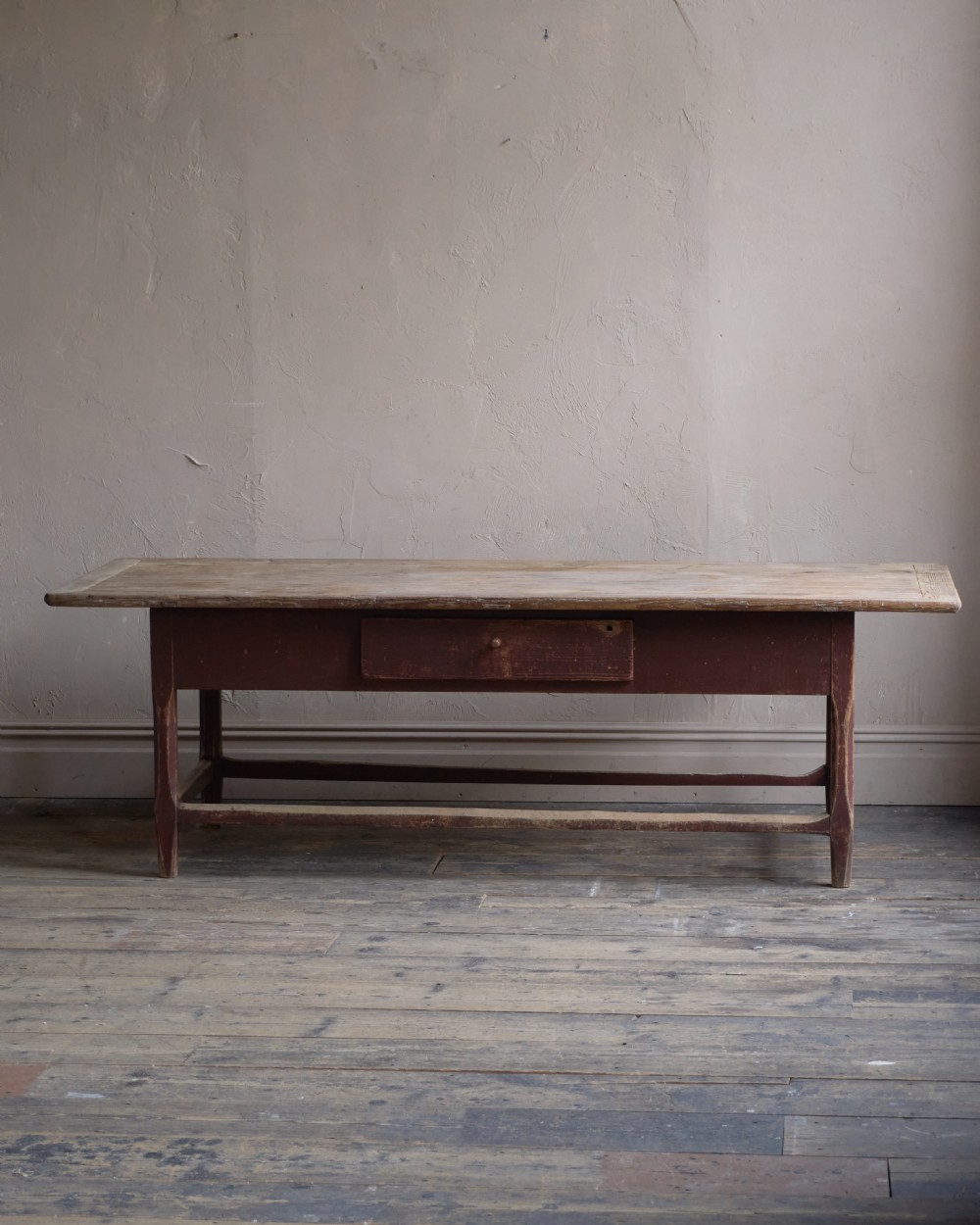 An antique Swedish kitchen table featuring an untreated scrubbed pine top, a single side drawer, and a Falu red painted apron and leg framework with stretchers. View VI