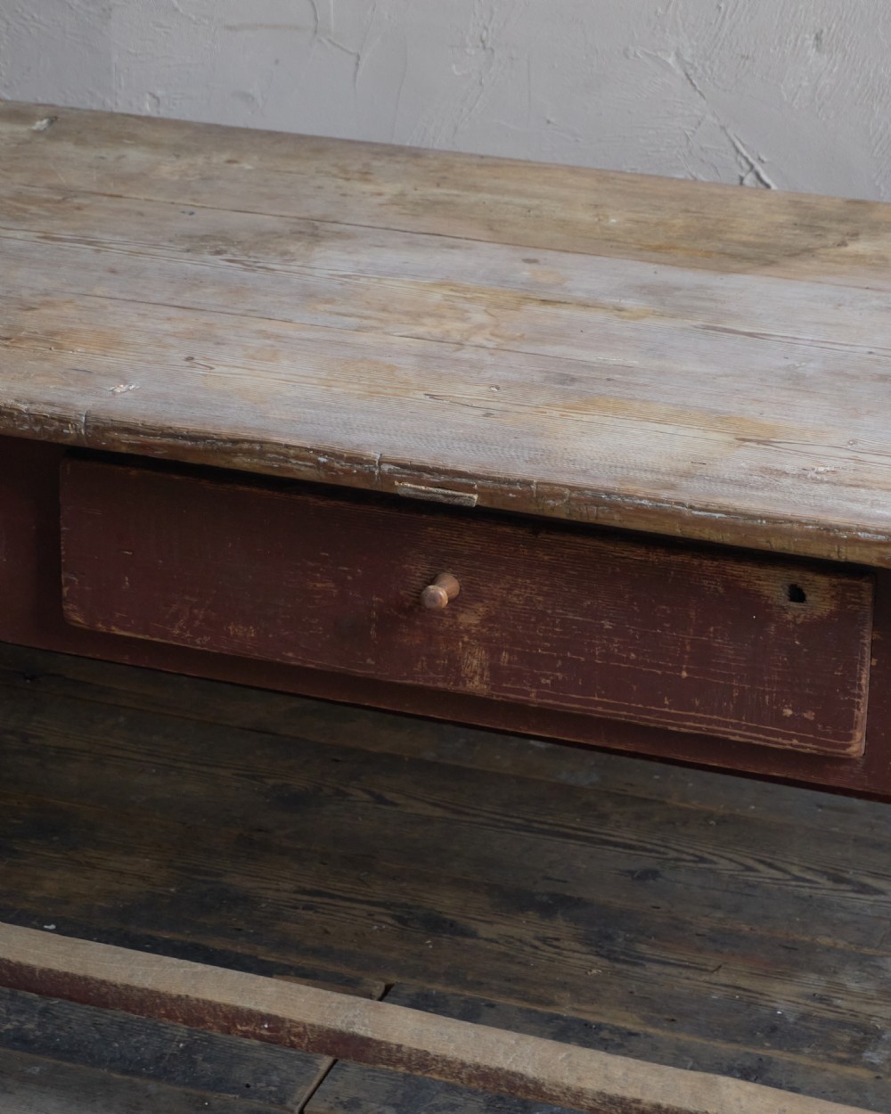 An antique Swedish kitchen table featuring an untreated scrubbed pine top, a single side drawer, and a Falu red painted apron and leg framework with stretchers. View VII