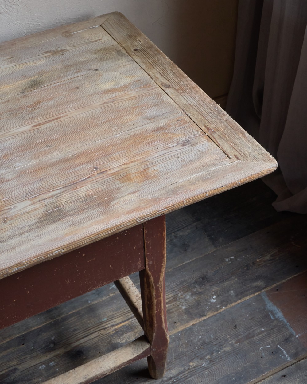 An antique Swedish kitchen table featuring an untreated scrubbed pine top, a single side drawer, and a Falu red painted apron and leg framework with stretchers. View X