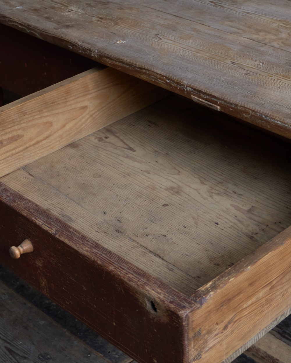 An antique Swedish kitchen table featuring an untreated scrubbed pine top, a single side drawer, and a Falu red painted apron and leg framework with stretchers. View XV